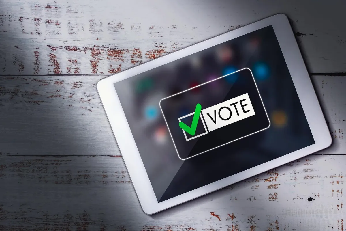 Tablette affichant une interface de vote en ligne posée sur un bureau